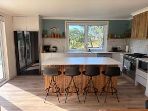 a kitchen with a table and four bar stools at Pouto Farms Packhouse - Coastal Farmhouse in Pouto