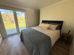 a bedroom with a bed and a large window at Pouto Farms Packhouse - Coastal Farmhouse in Pouto