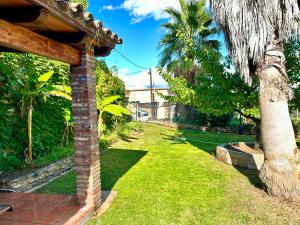 a yard with a brick house and a palm tree at Masia Pau Prat in Lliçà d'Amunt