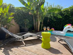 two glasses of wine sitting on a deck next to a pool at CALME - 15 min Toulouse - PISCINE - SPA in Mons