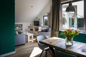 a living room with a table with a vase of flowers at Zeebungalows Terschelling in Formerum
