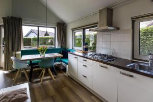 a kitchen with white cabinets and a table with a sink at Zeebungalows Terschelling in Formerum +8 photos