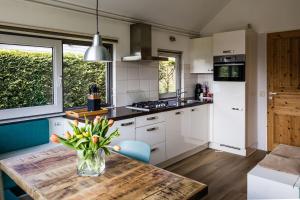 a kitchen with a table with a vase of flowers on it at Zeebungalows Terschelling in Formerum