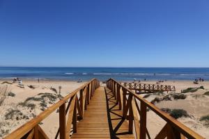 a wooden boardwalk leading to a beach with people at Casa La Mata in La Mata +10 photos