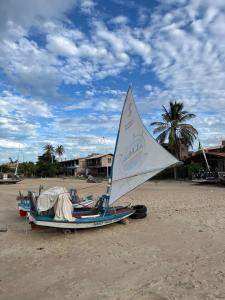 a boat with a sail on the beach at Casa por do sol Flecheiras in Flecheiras