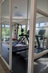 a gym with glass walls and a treadmill at Puerto Princesa Studio Condo with 2 Large Beds, Balcony, Pool & Gym in Puerto Princesa City