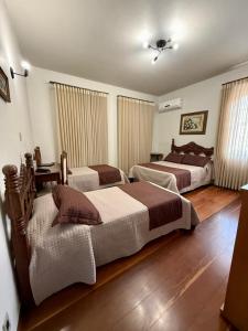 two beds in a room with wooden floors at Hotel Priskar in Ouro Preto