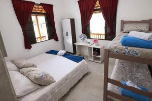 a bedroom with two bunk beds and two windows at Pouso Ravenala - Refúgio do viajante in Paraty