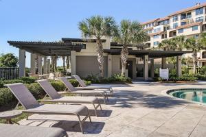a row of lounge chairs next to a swimming pool at Oceanfront condo with panoramic views, shared pool, and private washer & dryer in Fernandina Beach