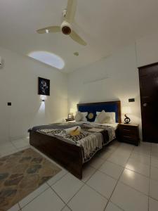 a bedroom with a bed and a ceiling fan at Rosewood Cottage in Karachi