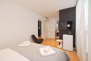 ein weißes Zimmer mit einem Bett und einem Fernseher in der Unterkunft Unique Integrated Hotel in Zadar