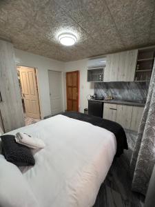 a bedroom with a large white bed and a kitchen at Inkinibe Self Catering in Windhoek +15 photos