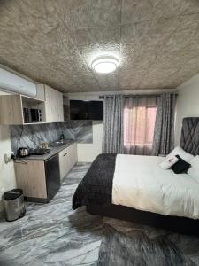 a bedroom with a large bed and a kitchen at Inkinibe Self Catering in Windhoek