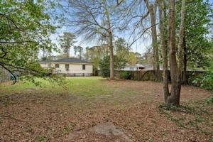 a yard with a house in the background with trees at Close-to-Everything Midtown Cottage in Hattiesburg