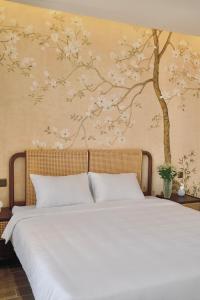 a bedroom with a bed with a tree mural on the wall at Mom Villa - Cẩm Thanh in Hiếu Nhơn