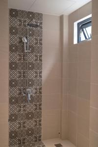 a shower in a bathroom with a tile wall at Mom Villa - Cẩm Thanh in Hiếu Nhơn +32 photos
