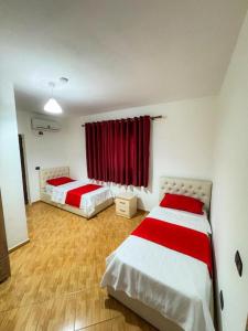 two beds in a room with a red curtain at Hotel Blu Mare Shengjin in Shëngjin
