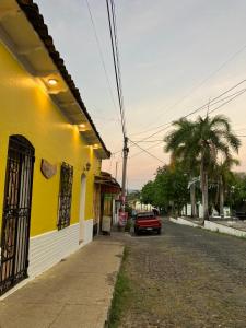 a red car parked next to a yellow building at Hostal El Amate #1 in Suchitoto +7 photos
