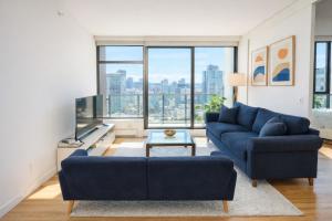 a living room with a blue couch and a large window at Pacific Pearl in Vancouver
