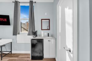 a white kitchen with a black refrigerator and a window at Guestic Hotel at Queen West in Toronto +22 photos