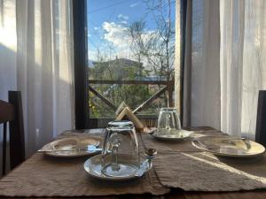 a table with plates and glasses on a table with a window at Casa Viedma in El Chalten