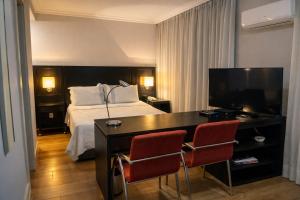 a hotel room with a bed and a desk with a television at Flat em Perdizes, perto da PUC e Allianz Parque in São Paulo