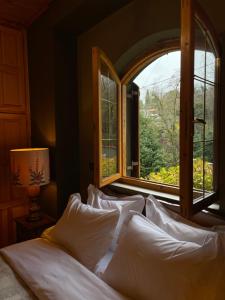 a bed with white pillows in a room with a window at Capris Rustic Ηouse with Mountain View in Archaia Feneos