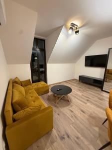 a living room with a yellow couch and a table at Apartman Mia 5 in Liptovský Mikuláš