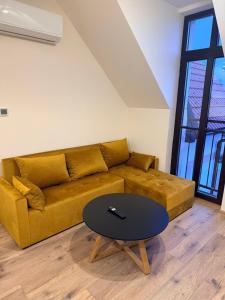 a living room with a yellow couch and a table at Apartman Mia 5 in Liptovský Mikuláš