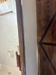 a bathroom with a wooden door next to a wall at REFUGIO do SAGRADO MORERE Tropical Lodge - A CASA das BRUXAS in Moreré