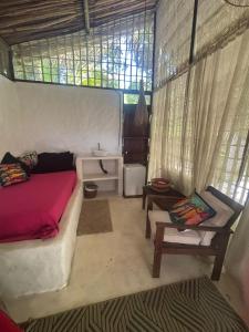 a bedroom with a bed and a table and a window at REFUGIO do SAGRADO MORERE Tropical Lodge - A CASA das BRUXAS in Moreré