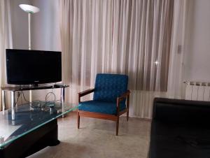 a living room with a blue chair and a television at Casa Encanto in Mar de las Pampas