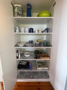 a kitchen pantry with plates and bowls on shelves at Sunny studio in the sky in Brenton-on-Sea