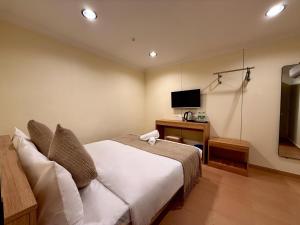 a bedroom with a bed and a desk and a television at Serene Turtle Hotel in Kuala Terengganu +24 photos