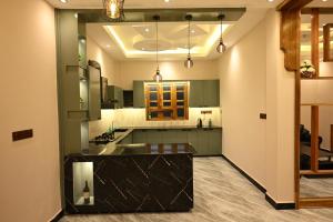 a kitchen with green cabinets and a black counter top at Sai Guest House in Chavakachcheri