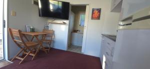 a small kitchen with a table and chairs and a television at Cozy corner on Cohen in Nelson +2 photos