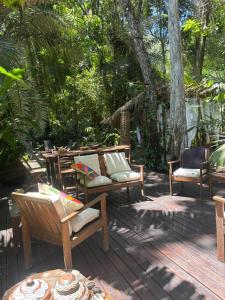 a wooden deck with chairs and tables and trees at REFUGIO do SAGRADO MORERE Tropical Lodge - A CASA das BRUXAS in Moreré