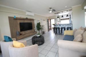 a living room with couches and a television and a kitchen at Laguna La Crete 119 in Uvongo Beach