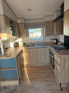 a kitchen with wooden cabinets and a sink and a window at Coastal Caravan Seton Sands in Port Seton +4 photos
