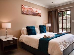 a bedroom with a bed with blue pillows and a window at The Orion Guesthouse in Middelburg