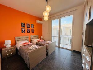 two beds in a room with an orange wall at Del Mar Apartment in Żebbuġ