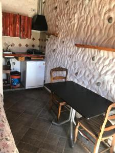 a kitchen with a table and two chairs and a refrigerator at Cabaña Tío Ale MONOAMBIENTES in El Bolsón
