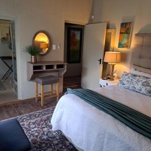 a bedroom with a bed and a table and a mirror at Kruger Tree Lodge in Marloth Park