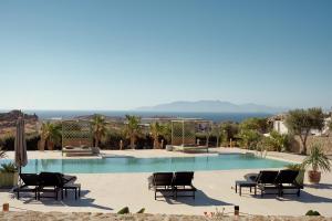 a swimming pool with chairs and the ocean in the background at Melisses in Mikonos