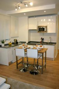 a kitchen with a wooden table and white chairs at Reina Sofía Acogedor in Madrid