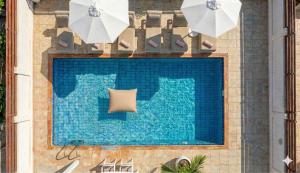 a swimming pool with two white umbrellas next to it at Fig Tree Beach Villa Five in Protaras