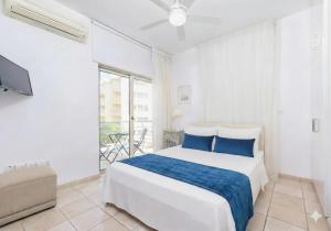 a white bedroom with a bed and a tv at Fig Tree Beach Villa Five in Protaras +16 photos