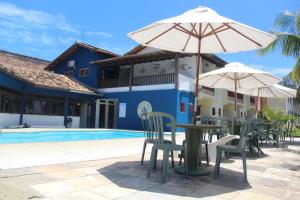 Eine Terrasse mit Tischen und Sonnenschirmen neben einem Pool in der Unterkunft Hotel Vale Verde Coroa Vermelha in Santa Cruz Cabrália + 49 Fotos