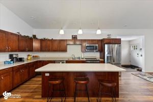 a kitchen with wooden cabinets and a kitchen island with bar stools at Soldotna-Kenai Peninsula House in Soldotna