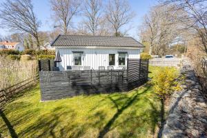 a small white house in a field of grass at Charmig stuga med havsutsikt in Karlskrona